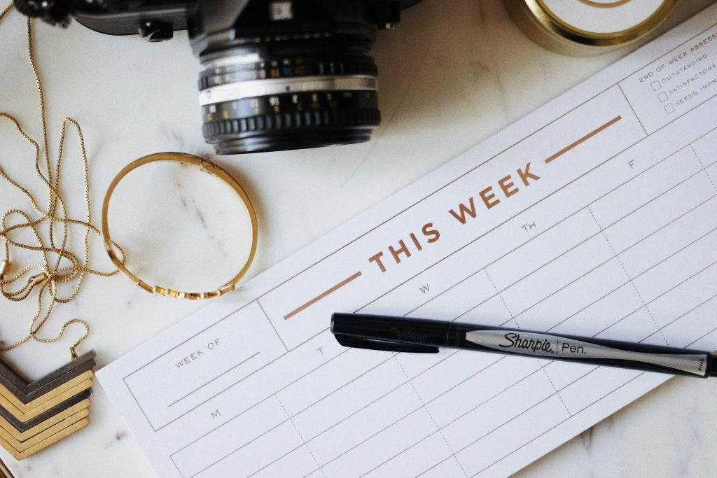 Photograph of a weekly planner with a pen resting on it